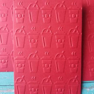May include: Red card stock with a repeating pattern of embossed coffee cups. Each cup has a lid, straw, and steam coming from the top.