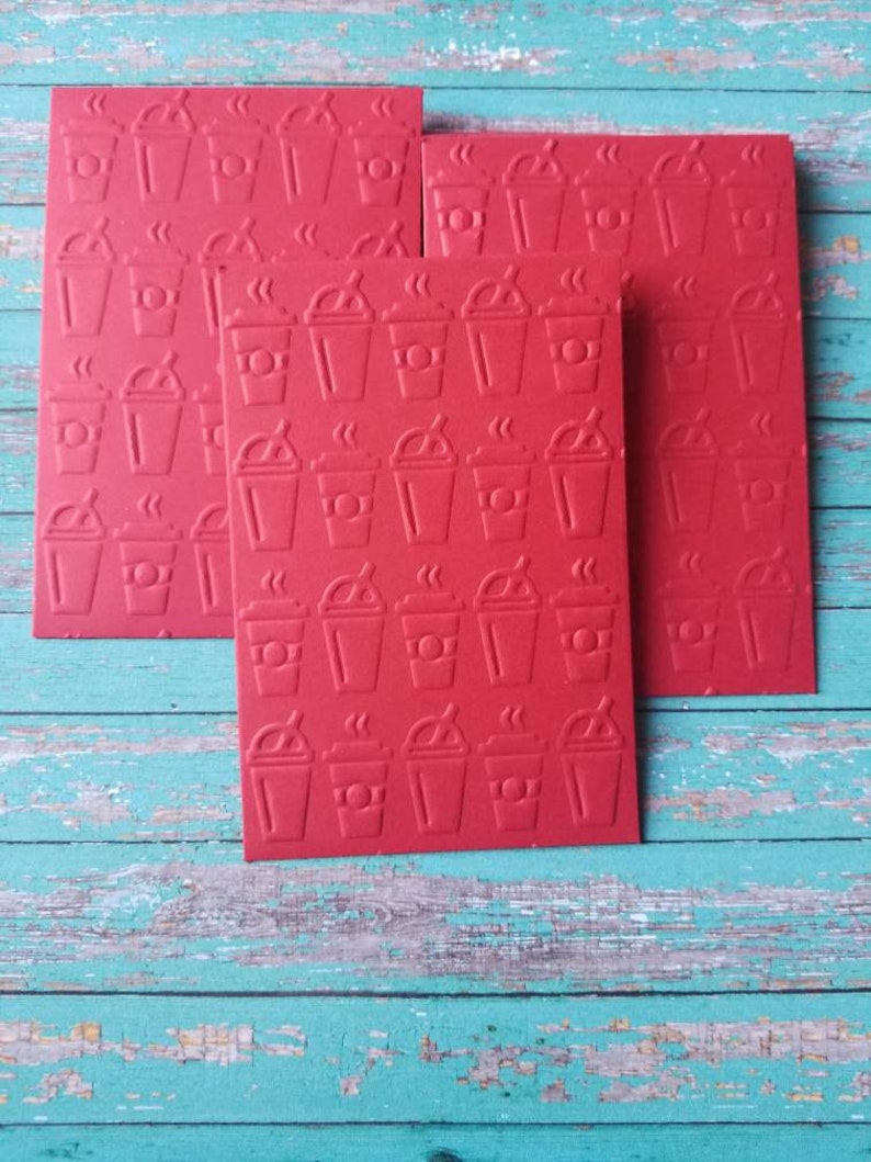 May include: Four red cards with a repeating pattern of a coffee cup with steam coming from the top. The cards are stacked on top of each other.