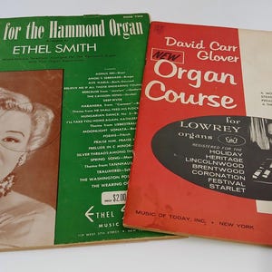 May include: Two vintage music books. One green book titled "Music for the Hammond Organ" by Ethel Smith, featuring a portrait. The other, a red book, is "Organ Course" by David Carr Glover, for Lowrey organs.
