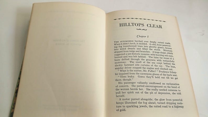 May include: Open vintage book with the title "HILLTOPS CLEAR" and "Chapter 1" visible. The pages are aged with text in black ink. The book is open, displaying the text on the right page.