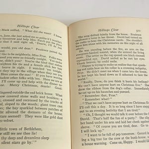 May include: Open book with text on aged paper. The pages display paragraphs of printed text, with the title "Hilltops Clear" at the top of the right page. The book is open on a white surface.