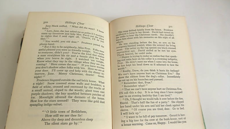 May include: Open book with text on aged paper. The pages display paragraphs of printed text, with the title "Hilltops Clear" at the top of the right page. The book is open on a white surface.