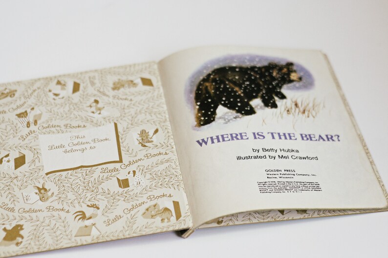 Op de afbeelding: Een vintage kinderboek getiteld "Waar is de beer?" door Betty Hubka, ge&iuml;llustreerd door Mel Crawford. De omslag toont een zwarte beer die door een besneeuwd landschap loopt. Het boek maakt deel uit van de Little Golden Books-serie.
