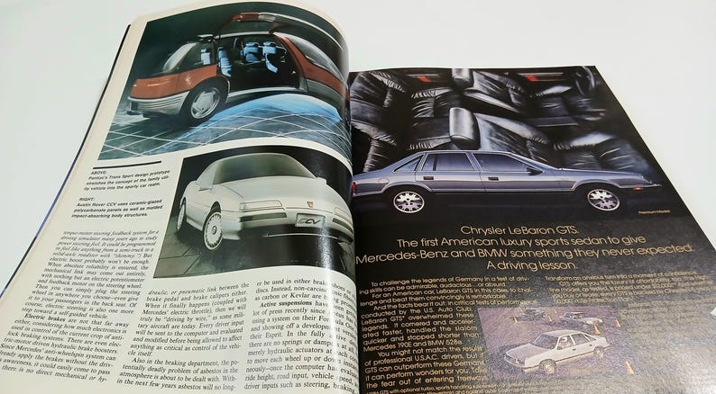 Puede incluir: Una p&aacute;gina doble de revista vintage con anuncios de autom&oacute;viles. La p&aacute;gina izquierda muestra un veh&iacute;culo conceptual Pontiac Trans Sport y un coche conceptual Pontiac Sunfire. La derecha presenta un sed&aacute;n Chrysler LeBaron GTS plateado.