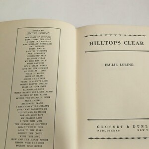 May include: Open book titled "Hilltops Clear" by Emilie Loring. The left page lists poems by the author. The right page displays the title and author's name. The publisher's name and location are at the bottom.
