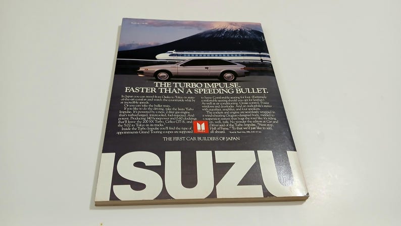 Puede incluir: Un anuncio de revista vintage de Isuzu que muestra un coche coup&eacute; plateado aparcado frente a un tren bala y el monte Fuji. El texto dice THE TURBO IMPULSE. FASTER THAN A SPEEDING BULLET. y THE FIRST CAR BUILDERS OF JAPAN con ISUZU en la parte inferior.