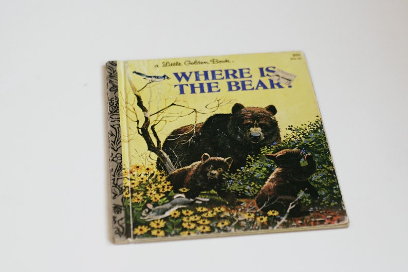 Op de afbeelding: Een vintage kinderboek met de titel "Waar is de beer?" met een gele kaft en illustraties van beren in een bosrijke omgeving.