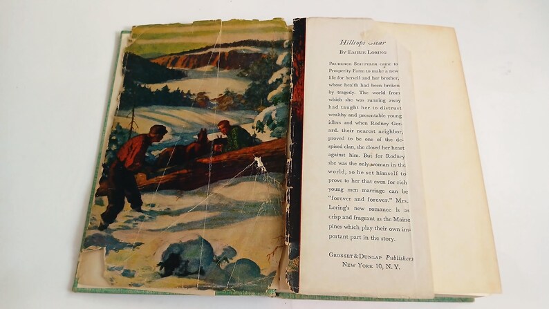 May include: Open vintage book titled "Hilltop Star" by Emilie Loring. The cover art depicts two men in a snowy landscape. The book's pages are yellowed with age, and the text is visible on the right page.