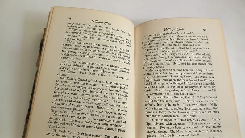 May include: Open book with text on aged pages. The pages are yellowed, and the text is in black. The book is open to two pages with text. The title "Hilltops Clear" is visible. The book appears to be an older edition.