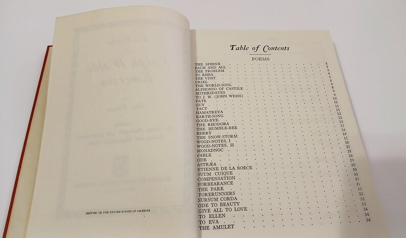 May include: Open book with a red spine, displaying the "Table of Contents" for a collection of poems. The page features a list of poems with corresponding page numbers, printed in black ink on off-white paper.