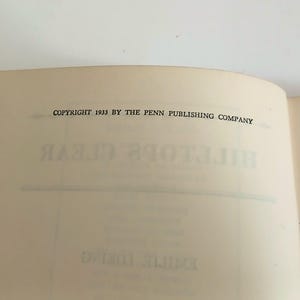 May include: Open book pages with text. The top page reads "COPYRIGHT 1933 BY THE PENN PUBLISHING COMPANY" in black font. The title "HILLTOP'S CLEAR" is visible in reverse on the page. The book's pages are off-white.