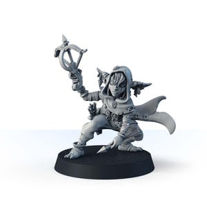 May include: A gray miniature figure of a fantasy character in a hooded cloak, kneeling on a black base. The figure holds a crossbow in one hand and a dagger in the other. The character has a stylized design with pointed ears and decorative elements.