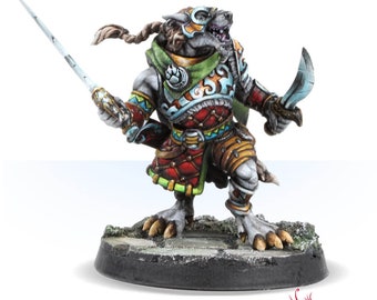 May include: A painted miniature figurine of a wolf-like creature wearing a colourful outfit and holding a sword and dagger. The figurine is standing on a circular base with a grey and green surface.