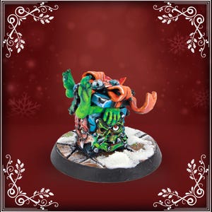 Peut inclure: Figurine miniature sur le thème de la fantaisie. Elle représente une pile de boîtes cadeaux vertes, rouges et bleues, surmontée d'une main verte et de rubans orange. La base est marron foncé avec un effet enneigé.
