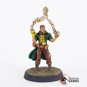 May include: A painted miniature figurine of a man wearing a green coat and brown pants, holding a swirling stack of cards in his right hand. The figurine is standing on a black base with green grass.
