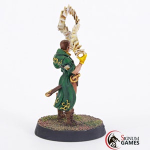 May include: A painted miniature figurine of a wizard holding a swirling book of spells. The wizard is wearing a green robe with gold accents and a brown belt. The miniature is standing on a round base.