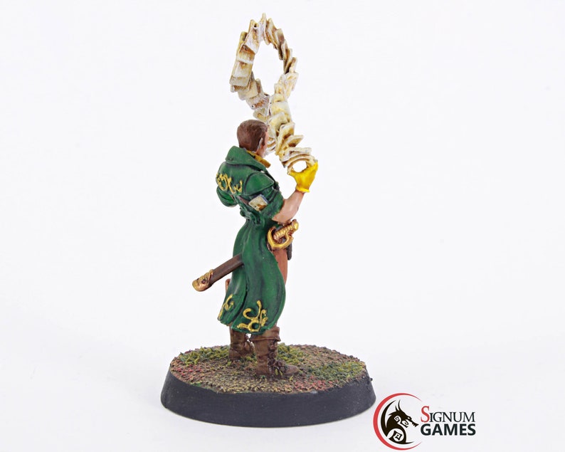 May include: A painted miniature figurine of a wizard holding a swirling book of spells. The wizard is wearing a green robe with gold accents and a brown belt. The miniature is standing on a round base.