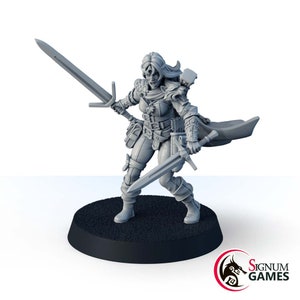 Może przedstawiać: Szara plastikowa figurka miniaturowa przedstawiająca wojowniczkę z mieczem w każdej ręce. Ma na sobie skórzaną kurtkę, płaszcz i buty. Stoi na okrągłej podstawie.