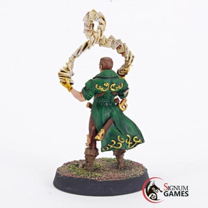 May include: A painted miniature figure of a wizard holding a swirling stack of papers in their left hand. The figure is wearing a green coat with gold accents and is standing on a round base.