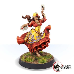 May include: A painted miniature figurine of a woman wearing a red and yellow dress, a headscarf, and holding playing cards. She is standing on a grassy base.