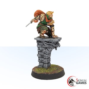 May include: A miniature fantasy figure of a warrior in green and gold armor, poised on a stone pedestal. The figure has a red cape and is holding a sword. The base is round and has a grass-like texture.