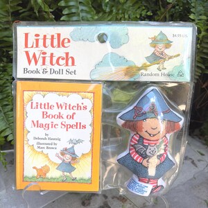 May include: A Little Witch Book & Doll Set in original plastic packaging. The set includes a small book titled Little Witch's Book of Magic Spells by Deborah Hautzig and a soft fabric doll of a witch wearing a blue hat and striped shirt.