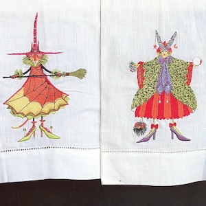 May include: Four white rectangular kitchen towels featuring colorful embroidered illustrations of whimsical figures. The designs include a character inside a red pumpkin, a witch with a broom, a figure in a patterned cloak, and a witch with a staff.