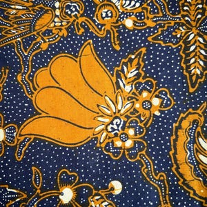 K&ouml;nnte beinhalten: Ein blauer Stoff mit einem wei&szlig;en Tupfenmuster und einem gelben Blumendesign. Das Blumendesign zeigt eine gro&szlig;e gelbe Blume mit wei&szlig;en und blauen Akzenten.