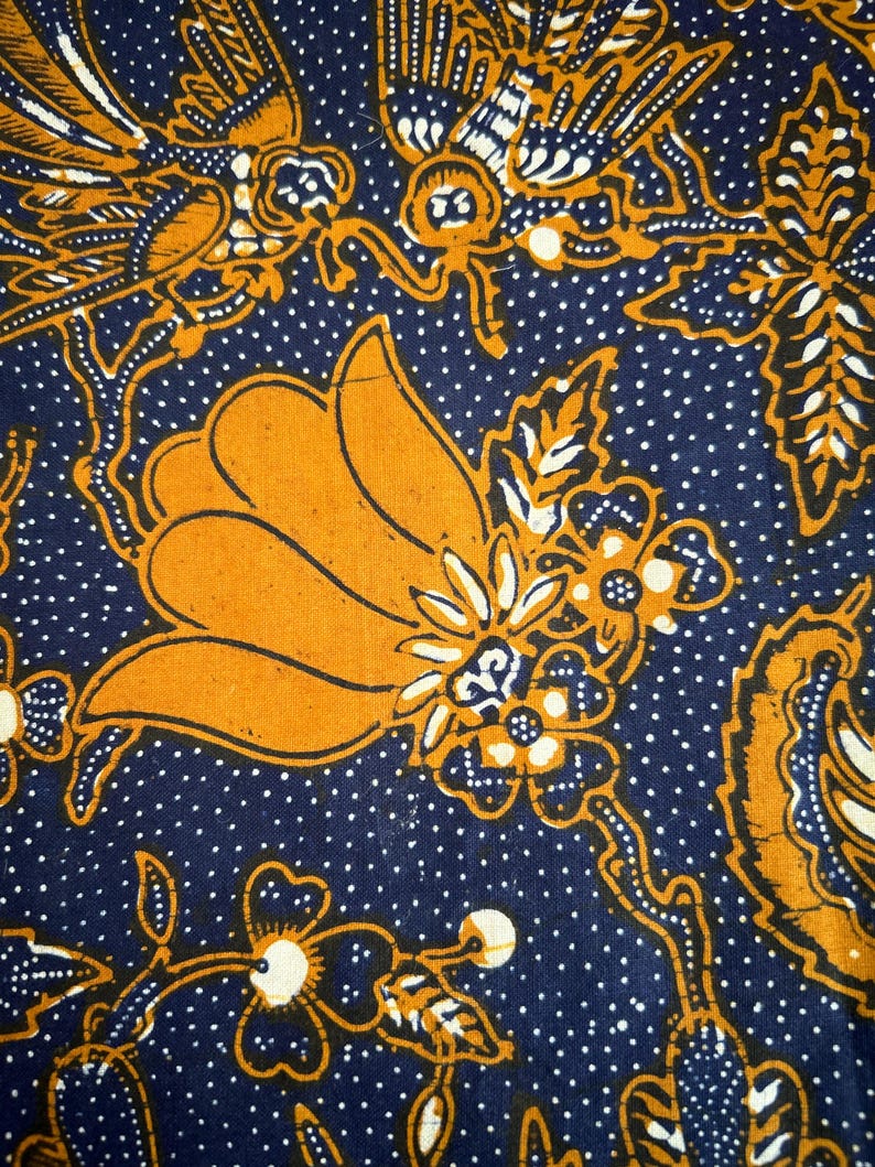 K&ouml;nnte beinhalten: Ein blauer Stoff mit einem wei&szlig;en Tupfenmuster und einem gelben Blumendesign. Das Blumendesign zeigt eine gro&szlig;e gelbe Blume mit wei&szlig;en und blauen Akzenten.