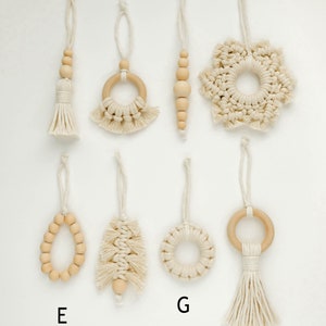 May include: Eight handmade macrame ornaments with wooden beads and rings. The ornaments are in the shape of a tassel, a ring, a snowflake, a beaded strand, a tree, a circle, and a tassel with a ring.
