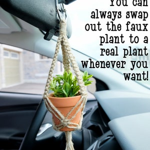 May include: A small potted plant hangs from the rear view mirror of a car using a macrame plant hanger. The text "You can always swap out the faux plant to a real plant whenever you want!" is visible in the image.
