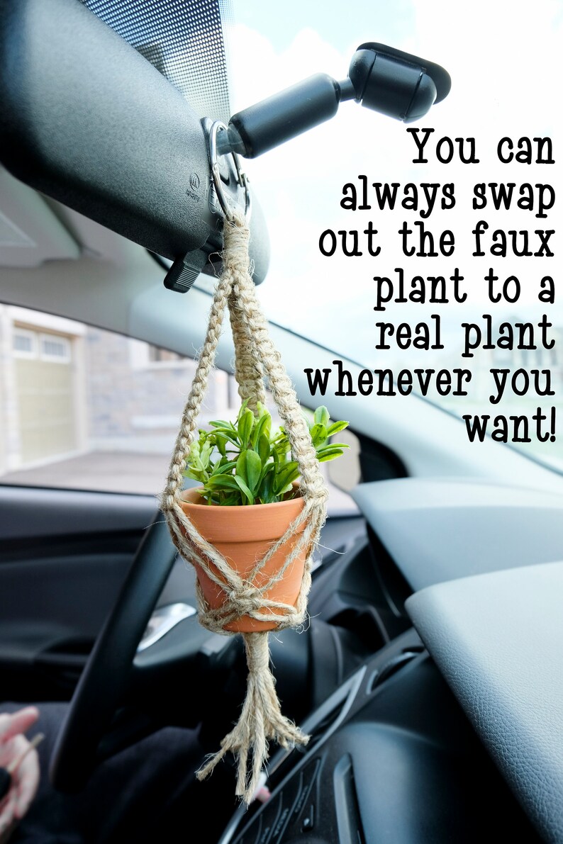 May include: A small potted plant hangs from the rear view mirror of a car using a macrame plant hanger. The text "You can always swap out the faux plant to a real plant whenever you want!" is visible in the image.