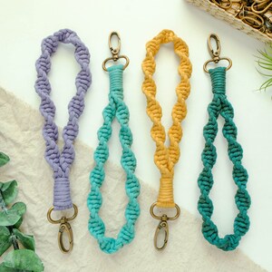 May include: Three colourful braided lanyards with metal clasps. The lanyards are purple, teal and yellow.