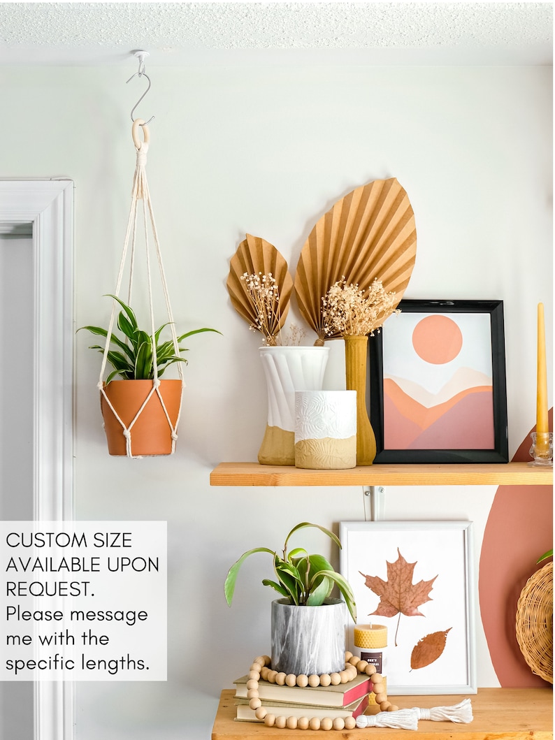 May include: A shelf with a variety of home decor items, including a hanging plant, a vase with dried flowers, a framed print with a sunset landscape, and a framed print with a pressed leaf. The shelf is made of wood and has a light brown finish. The text "CUSTOM SIZE AVAILABLE UPON REQUEST. Please message me with the specific lengths." is visible on the image.