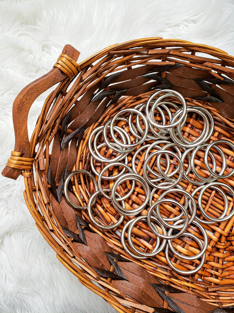 May include: A wicker basket filled with silver metal rings. The basket is brown and has a woven pattern.