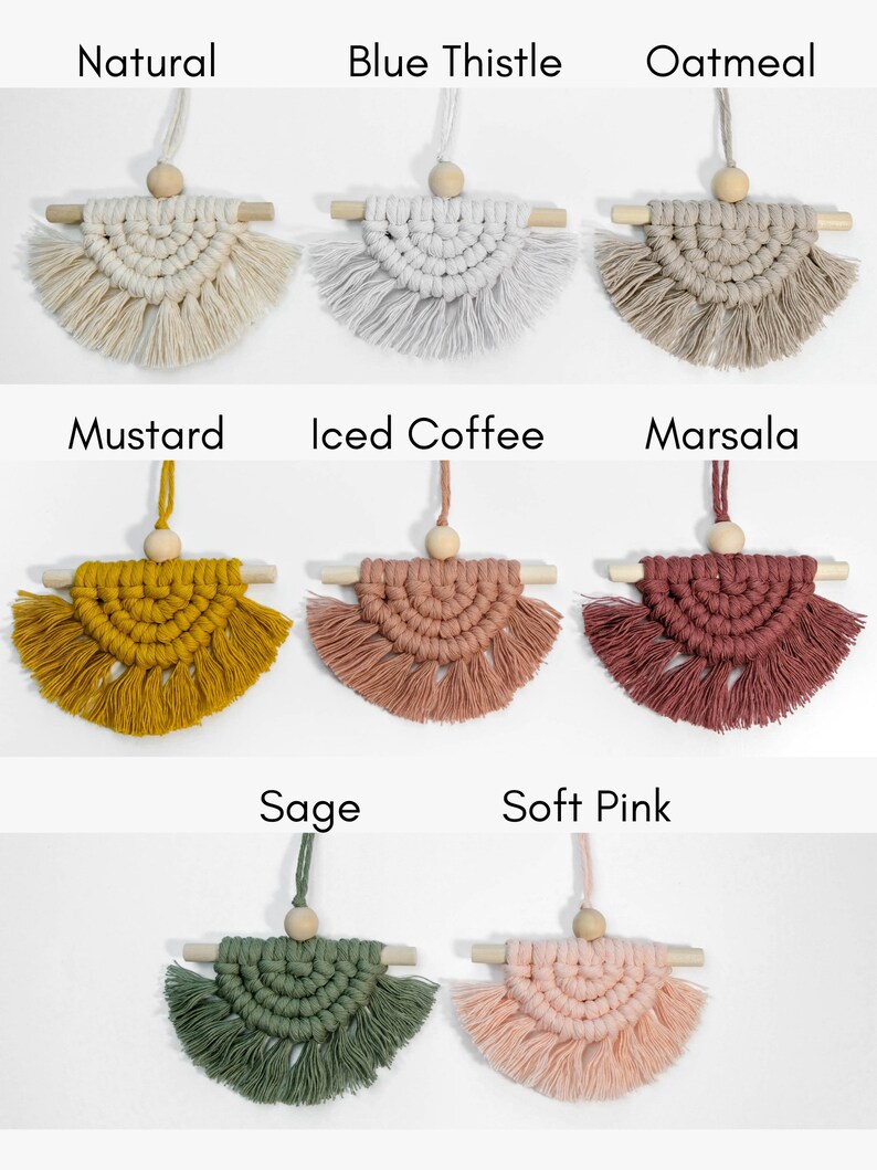May include: Nine macrame wall hangings in various colors, including natural, blue thistle, oatmeal, mustard, iced coffee, marsala, sage, and soft pink. Each hanging features a wooden dowel and a wooden bead.