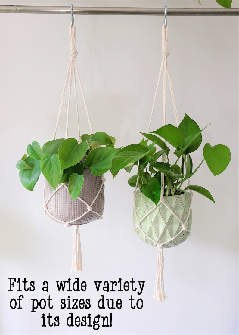 May include: Two macrame plant hangers with white cotton cord and tassels, each holding a potted plant. The plant on the left is in a gray pot, and the plant on the right is in a green pot. The text "Fits a wide variety of pot sizes due to its design!" is at the bottom of the image.