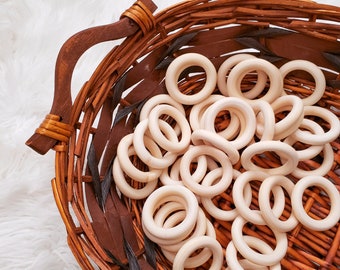 May include: A wicker basket filled with a large quantity of natural wood teething rings. The rings are smooth and unpainted, perfect for babies to chew on.