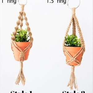 May include: Two macrame plant hangers with different sized rings. The left hanger has a 1 inch ring and the right hanger has a 1.5 inch ring. Both hangers are made with natural jute rope and have a tassel at the bottom. The hangers are holding small terracotta pots with green plants.