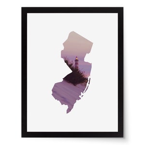 May include: Framed art print featuring the silhouette of the state of New Jersey, filled with a scenic view of a lighthouse at dusk. The artwork is set against a white background and framed in black.