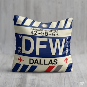 May include: A white cushion with a blue and white striped pattern. The cushion features a luggage tag design with the text "BAGGAGE STRAP TAG 42-58-63 DFW DALLAS FORT WORTH" printed on it.