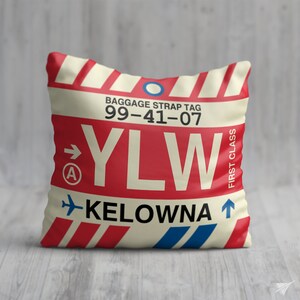 May include: A white and red luggage tag with the text "BAGGAGE STRAP TAG 99-41-07 YLW KELOWNA" and a blue airplane icon. The tag has a red stripe with a white arrow pointing to the right and the letter "A" inside a circle.
