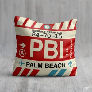 May include: A white and red luggage tag with the text "BAGGAGE STRAP TAG 84-70-15 PBI PALM BEACH" and a blue airplane icon.