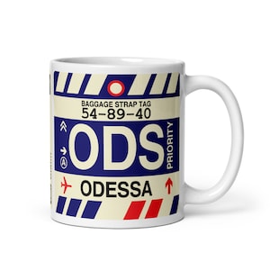 Puede incluir: Taza de cerámica blanca con un diseño de etiqueta de equipaje. El diseño incluye las letras "ODS", la palabra "ODESSA" y el texto "BAGGAGE STRAP TAG 54-89-40". La taza tiene un asa blanca y un interior blanco.