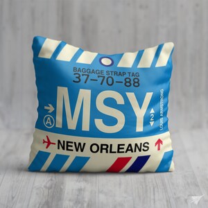 May include: A blue and white luggage tag with the text "BAGGAGE STRAP TAG 37-70-88" and "MSY NEW ORLEANS" with an arrow pointing to the right. The tag also has the text "LOUIS ARMSTRONG" and an arrow pointing up.