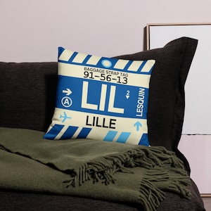May include: A decorative throw pillow featuring a blue and white airport luggage tag design. The tag reads "BAGGAGE STRAP TAG 91-56-13 LIL LILLE LESQUIN".