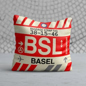 May include: Red and white luggage tag with the text "BAGGAGE STRAP TAG 38-15-46 BSL BASEL" and a small airplane icon. The tag also has a blue circle and an arrow pointing to the left with the letter "A" inside.