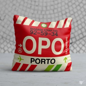 May include: Red and white luggage tag with the text "BAGGAGE STRAP TAG 92-59-34 OPO PORTO SA CARNEIRO" and a green arrow pointing up.