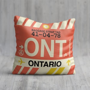 May include: A red and white pillow with a luggage tag design. The tag says "ONTARIO" and "ONT" with the airport code "41-04-78".