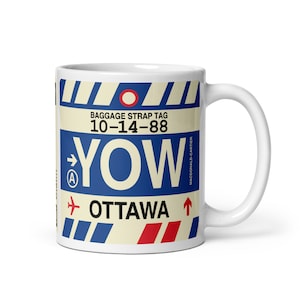 May include: White ceramic mug featuring a vintage baggage tag design. The design includes the text "YOW OTTAWA" in blue, red, and white, with the date "10-14-88" and the words "BAGGAGE STRAP TAG". The mug has a curved handle.
